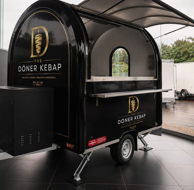 Zwarte foodtrailer met goudkleurig logo in een showroom